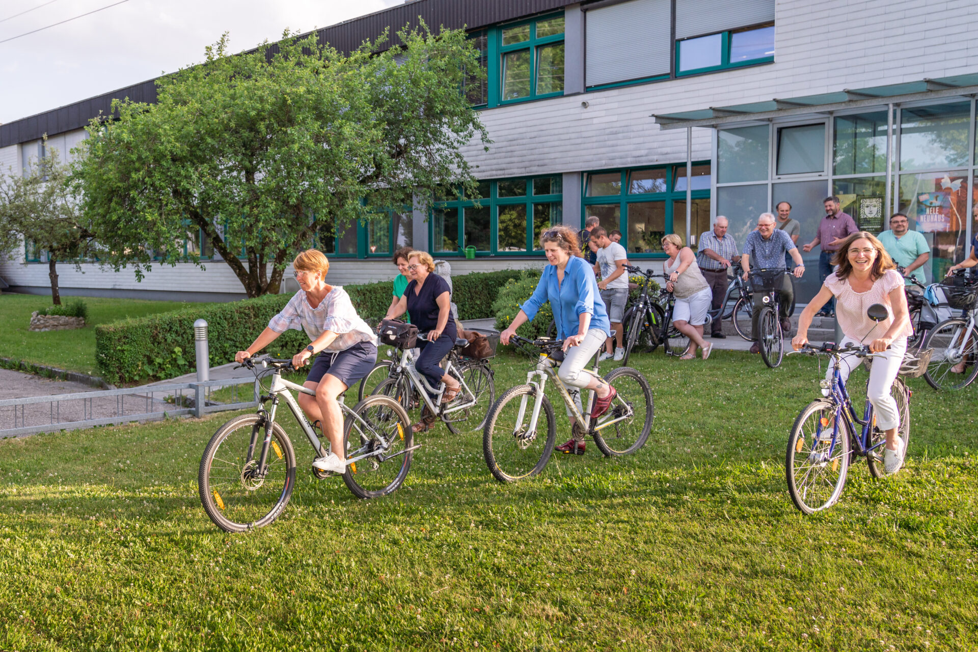 Mandatarinnen radeln über Wiese vor Gemeindeamt