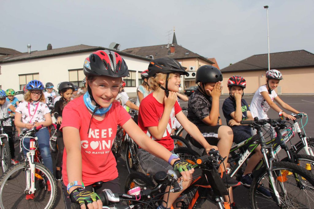 Eine Gruppe von Kindern warten mit Fahrrad und Helm, dass sie losfahren dürfen