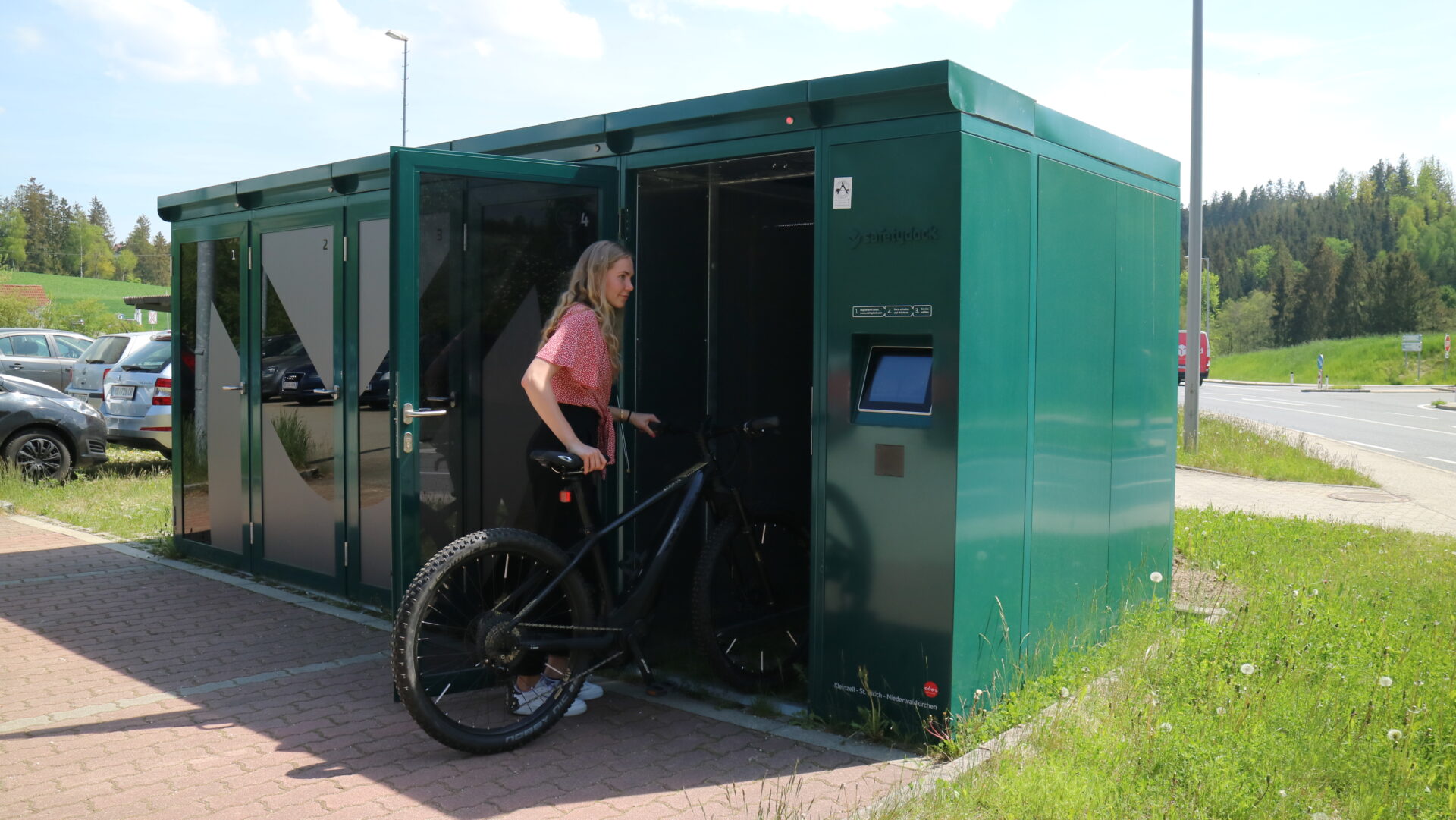 Frau schiebt Fahrrad in Radbox