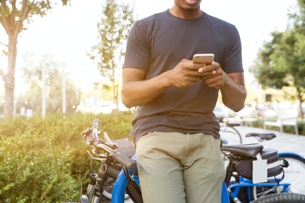 Ein Herr lehnt am Fahrrad und blickt auf sein Handy