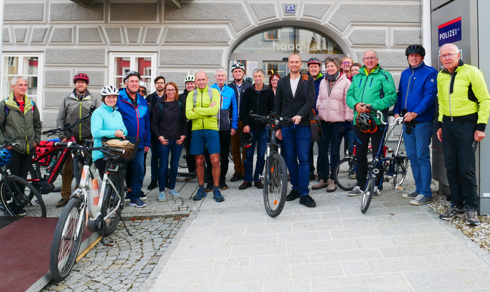 Eine Gruppe von Personen steht mit Fahrrädern vor der Marktgemeinde Haag am Hausruck