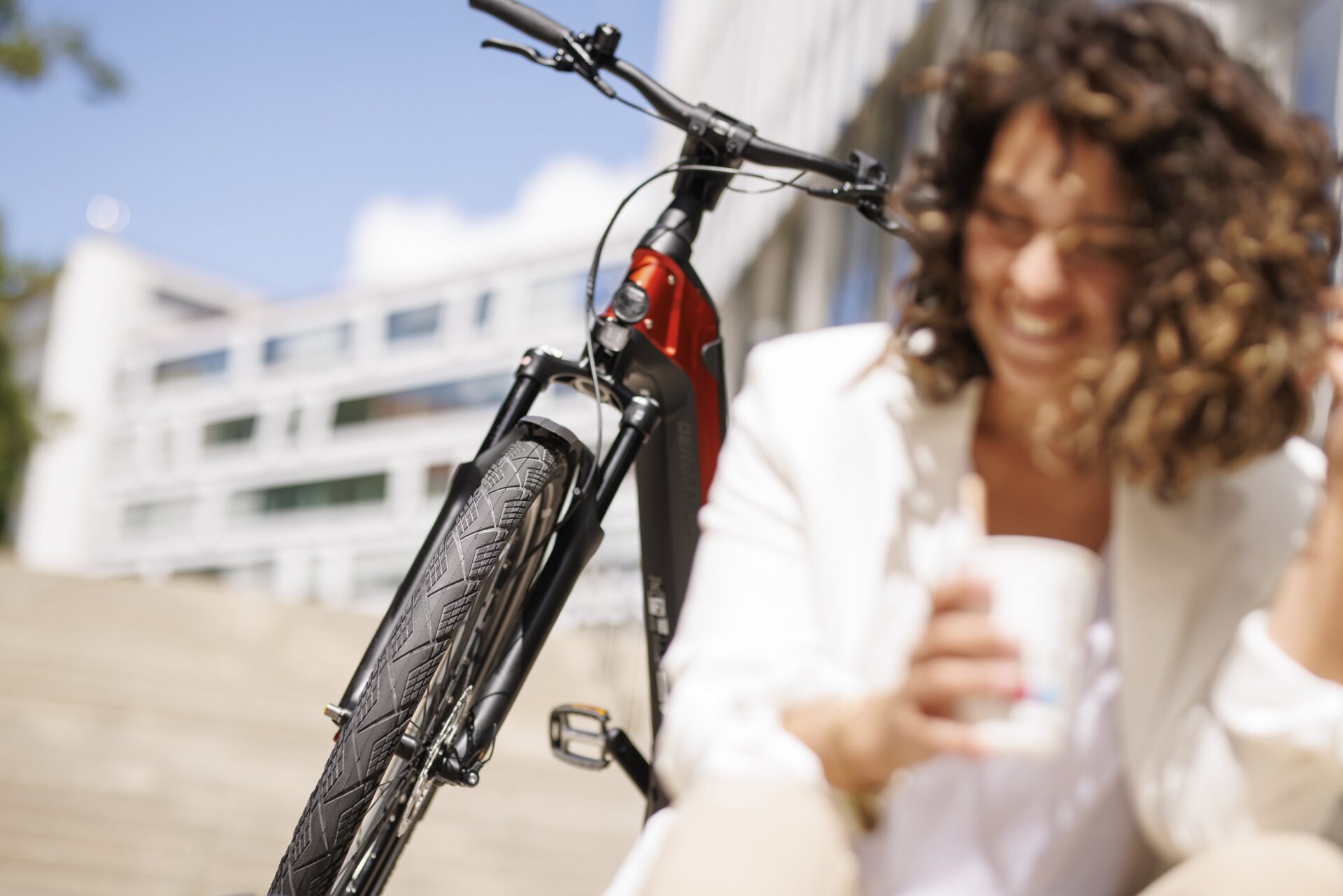 Dame sitzt mit Coffee to go Becher vor ihrem Jobrad