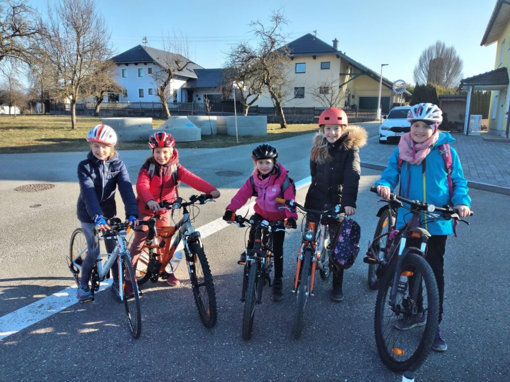 5 Schülerinnen posieren mit Fahrrad und Helm