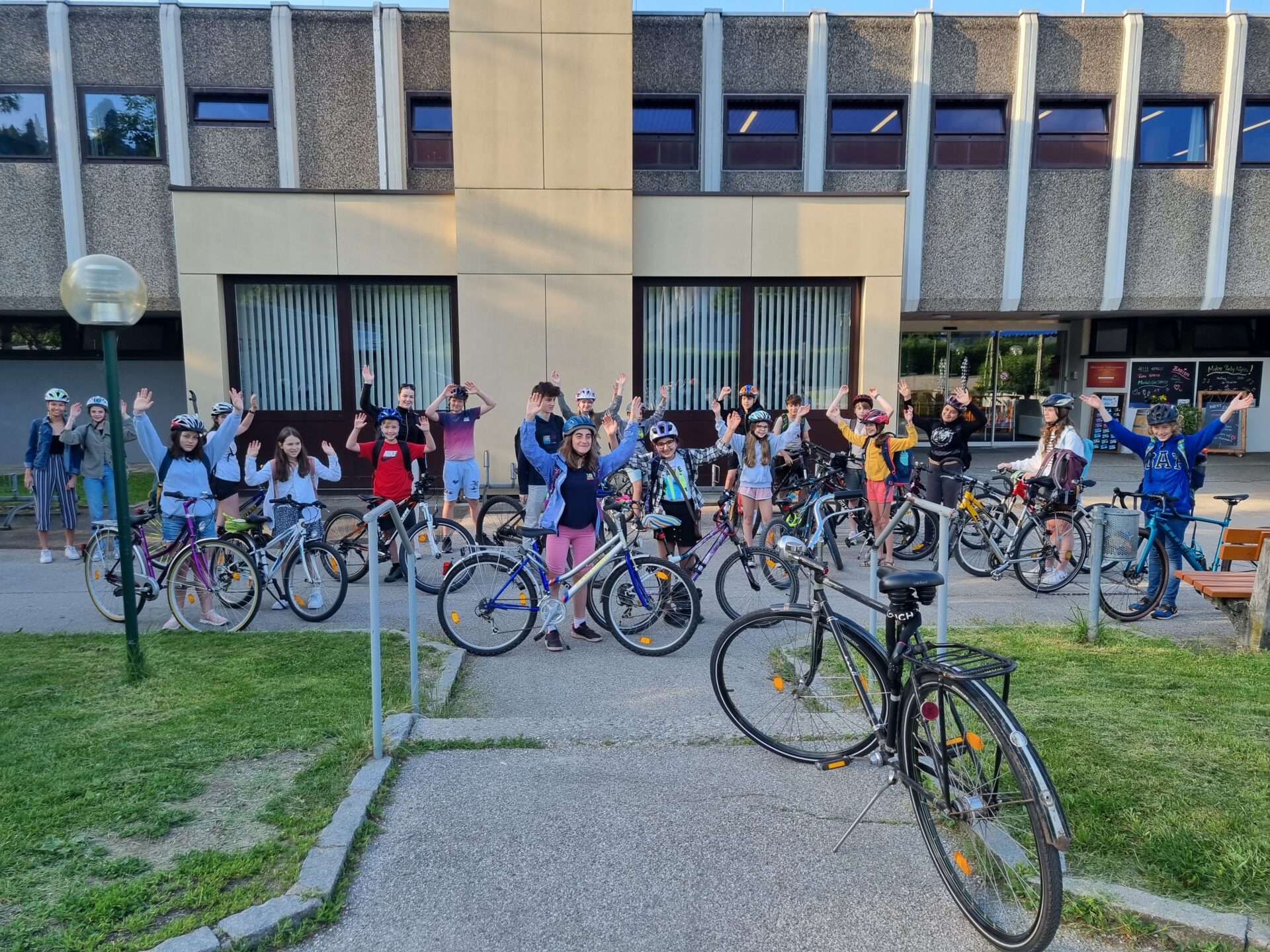 Schüler:innen des Europagymnasium Auhof posieren mit Fahrrad vor der Schule. Sie halten alle beide Hände in die Höhe.