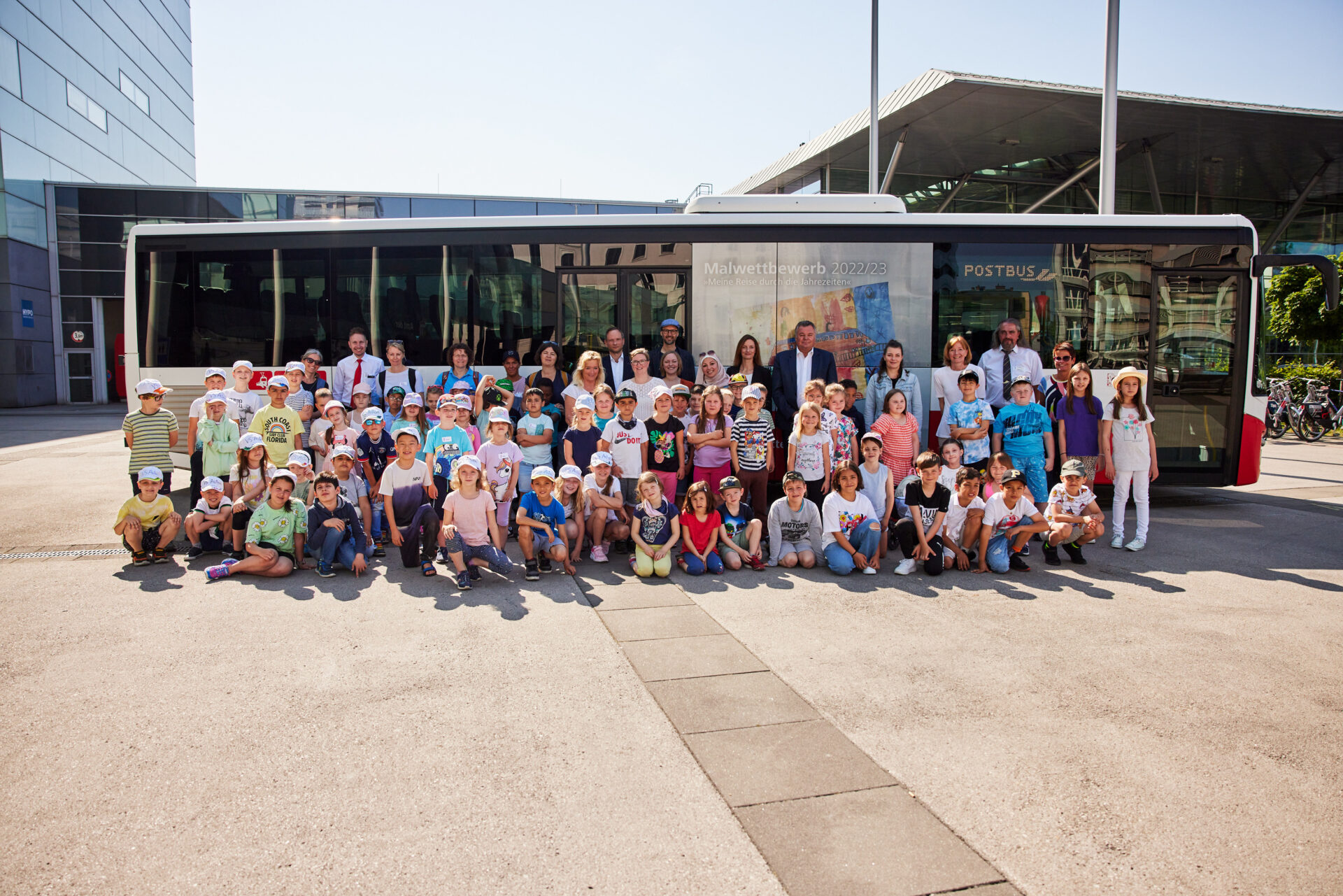 Volksschüler:innen posieren vor einem Postbus mit Mahlwettbewerb-Aufdruck.