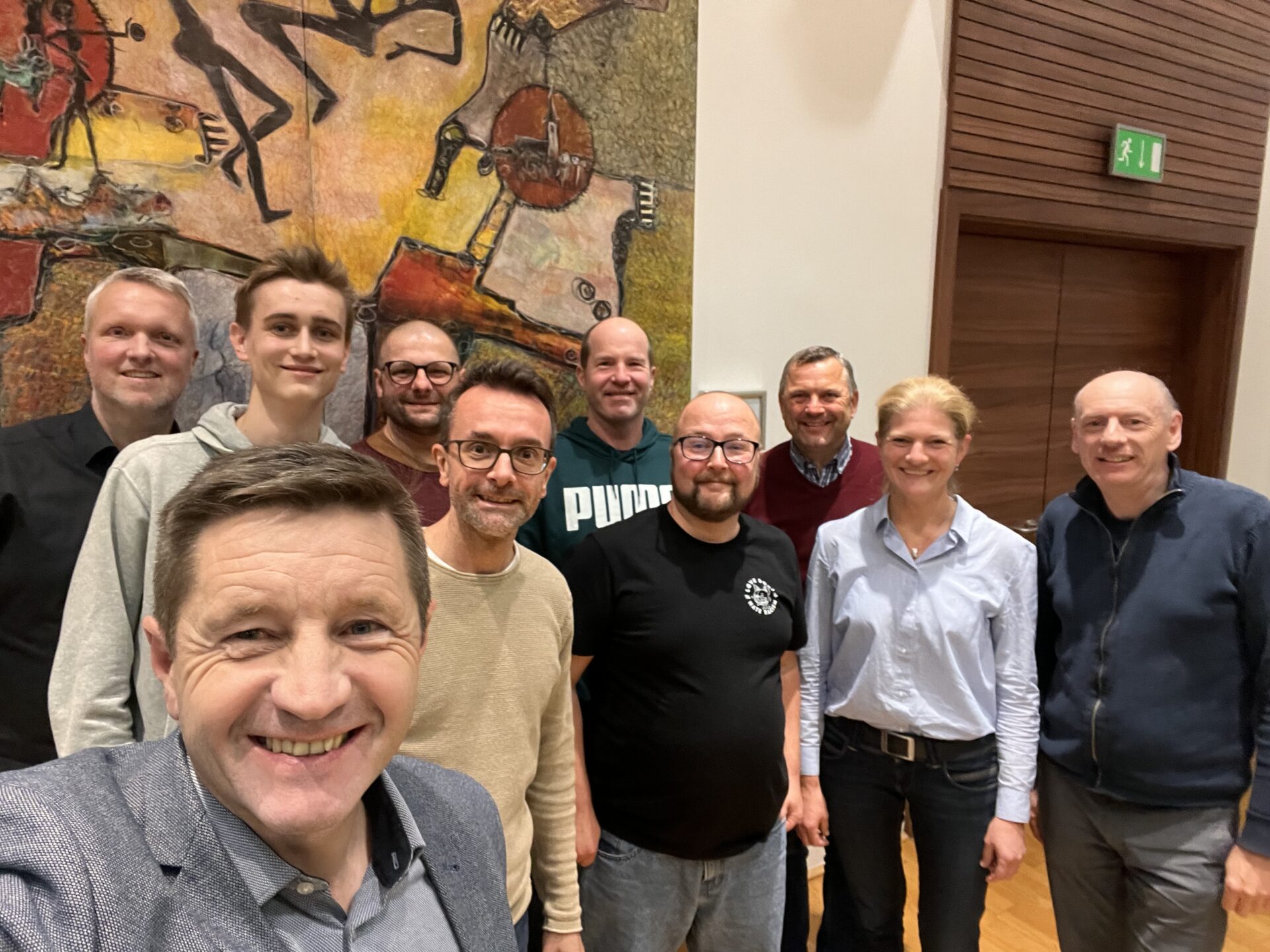 Gruppenselfie von mehreren Menschen in einem Saal