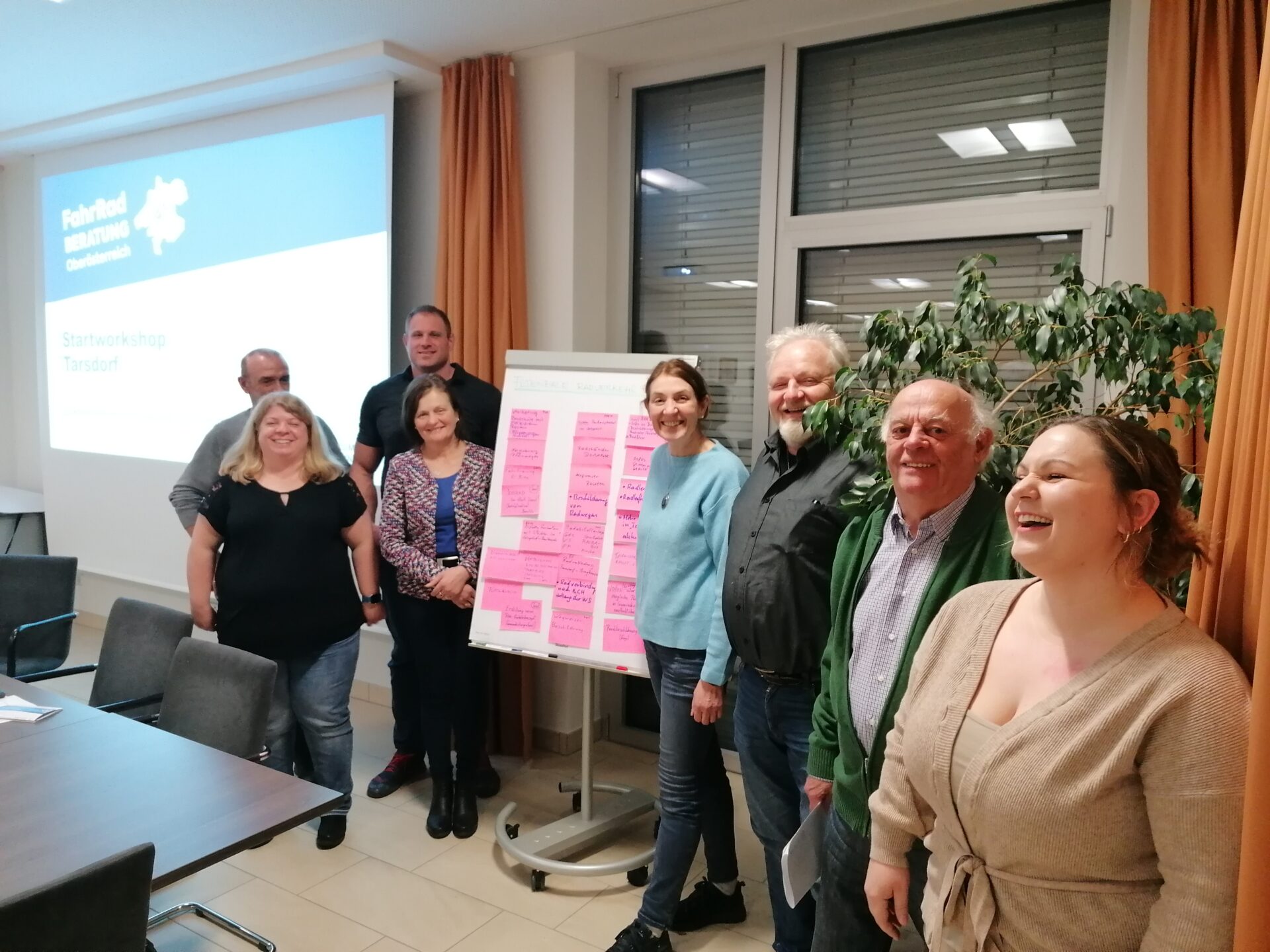 mehrere Personen in einer Reihe aufgestellt, neben einem Flipchart