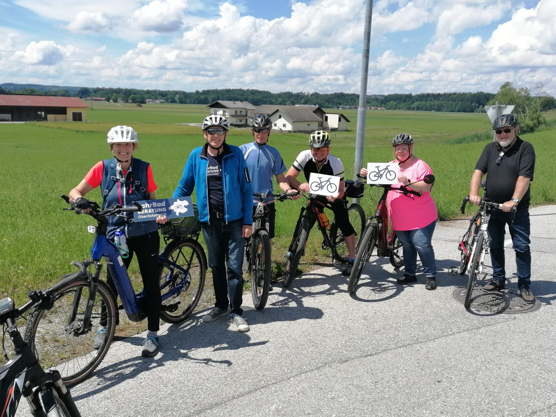 Gruppe von Radfahrenden vor flacher agrarisch geprägter Landschaft