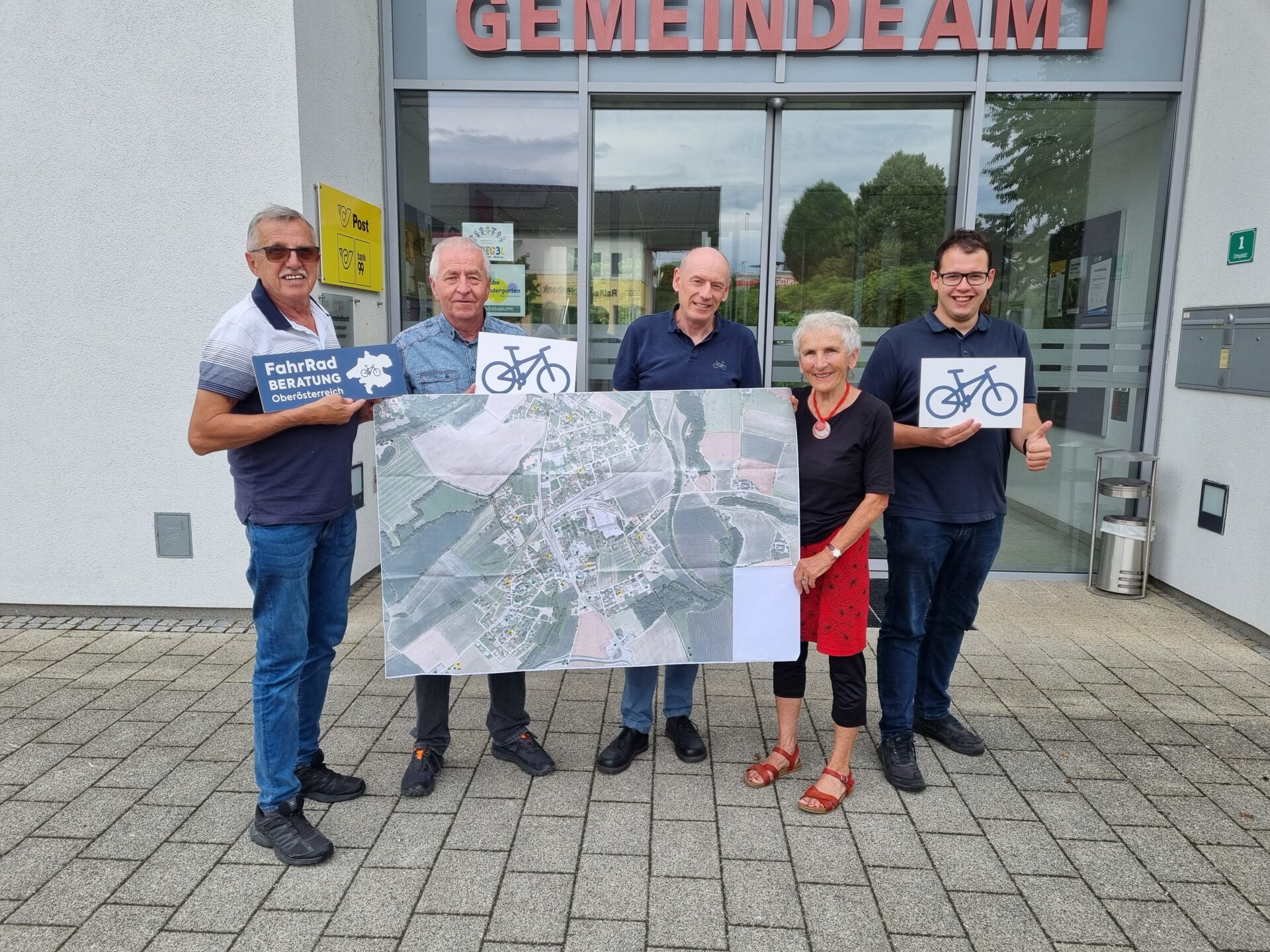 Gruppe von fünf Menschen, die einen ausgedruckten Ortsplan und Fahrradschilder halten