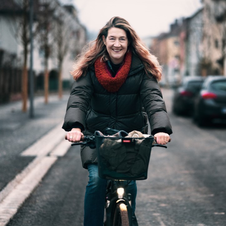 Frau in Wintermantel fährt direkt auf Kamera zu, Portraitfoto der Verkehrsstadträtin von Vöcklabruck