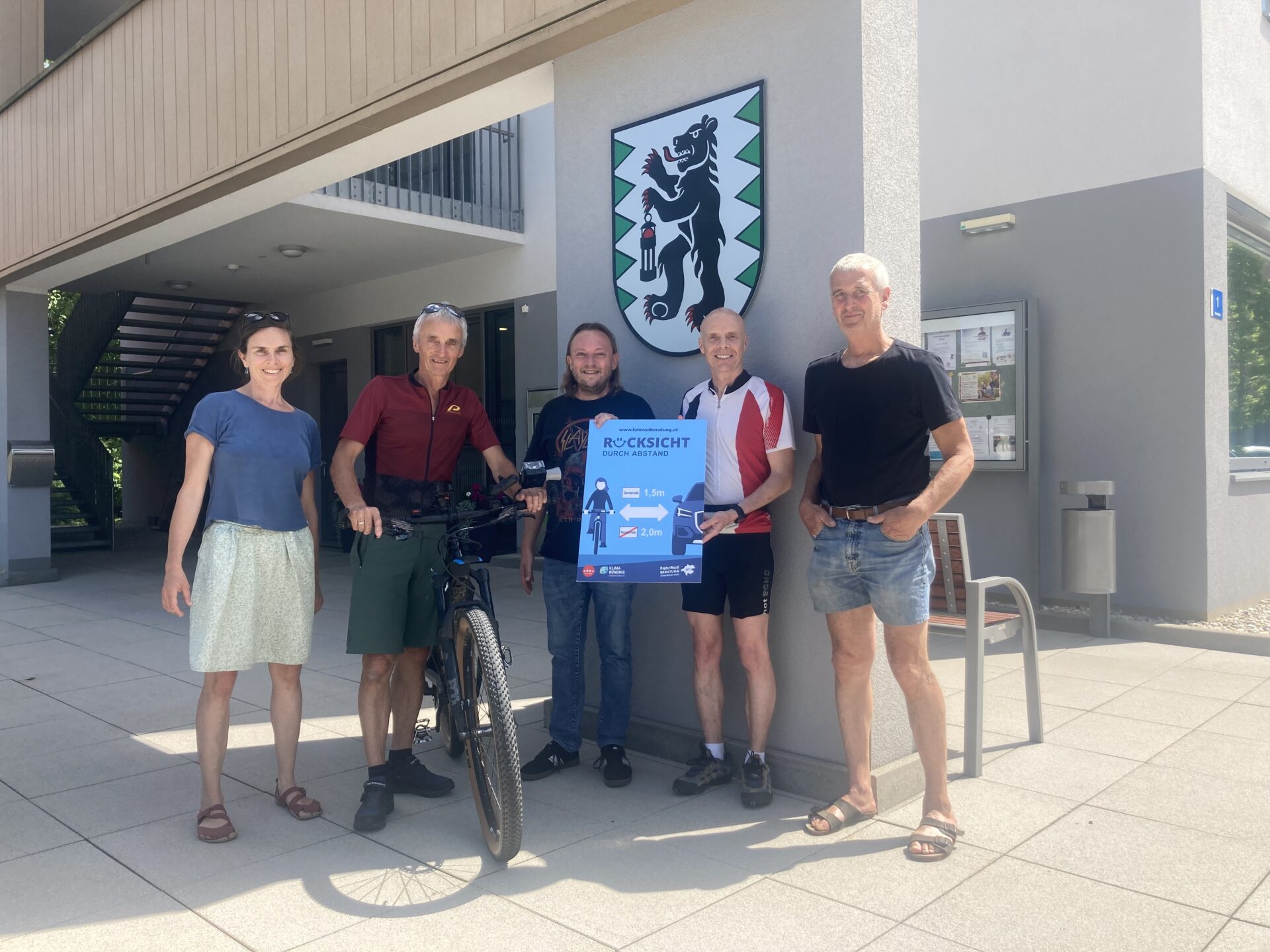 Gruppe von 5 Personen mit einem Rad und Schild, das auf richtigen Überholabstand aufmerksam macht