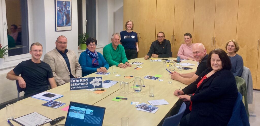 Eine Gruppe sitzt an einem Tisch in einem Besprechungsraum.